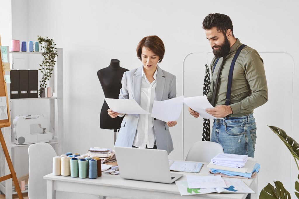 Team of designers reviewing design drafts in a modern studio, highlighting collaboration and creativity in fast embroidery digitizing services.